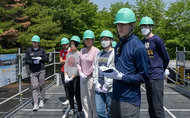 戴安全帽时, 电竞赌博平台团队聆听东京电力公司代表解释核电站的布局和导致熔毁的事件.